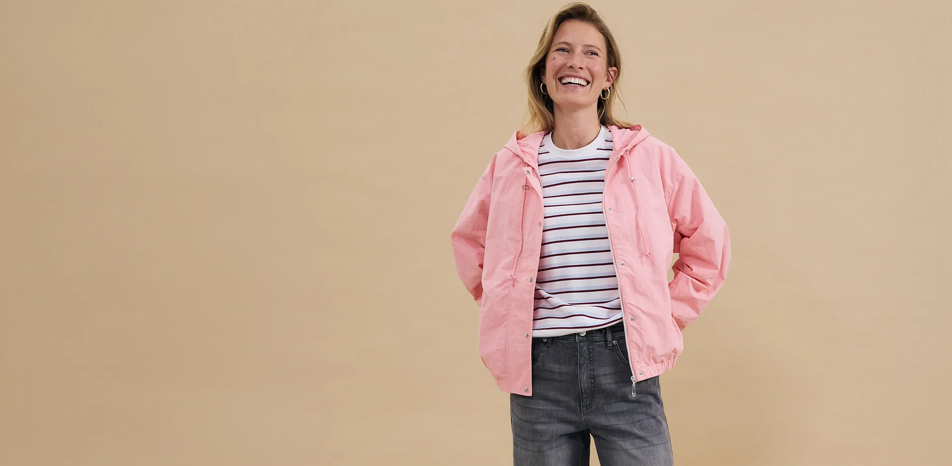 Blouson rose sur un T-shirt rayé, associé à un jean gris - un look décontracté pour les loisirs.