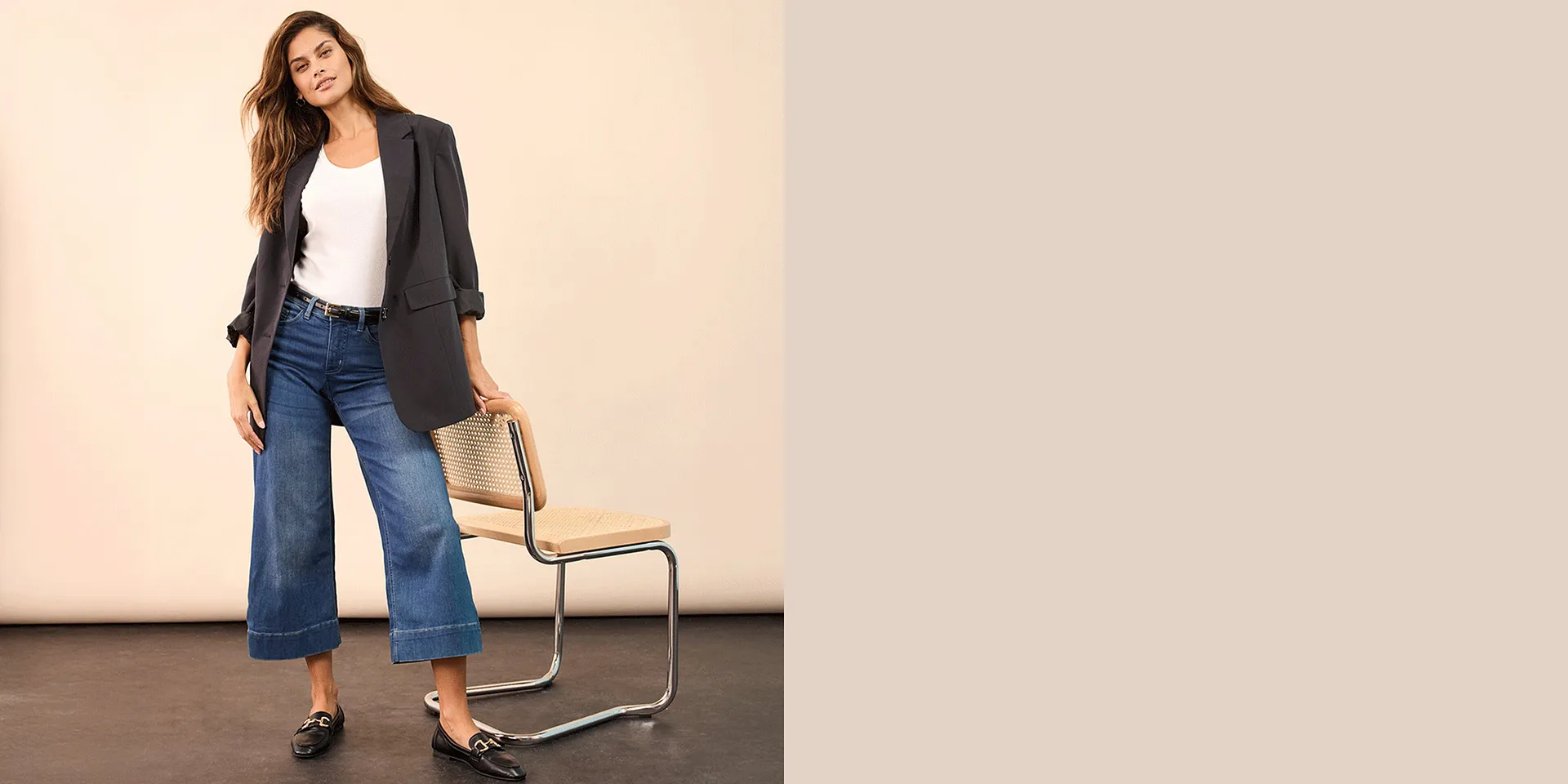 Blazer gris élégant associé à un top blanc, un jean large et des mocassins noirs.