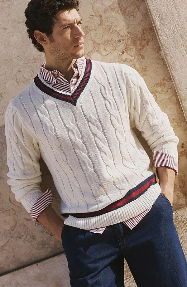 Pull blanc à torsades superposé sur une chemise, associé à un jean.