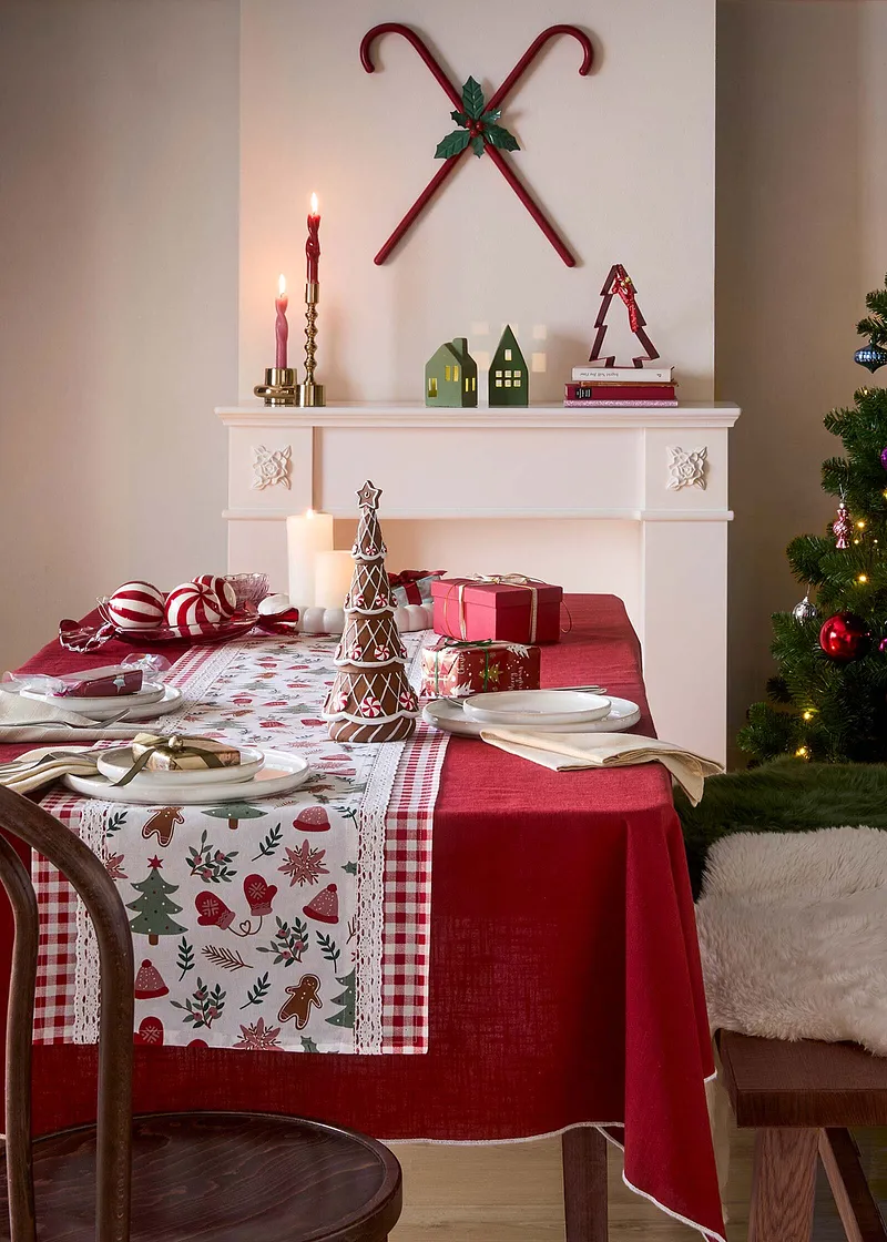 Table dressée pour les fêtes avec une nappe agrémentée de motifs de Noël.