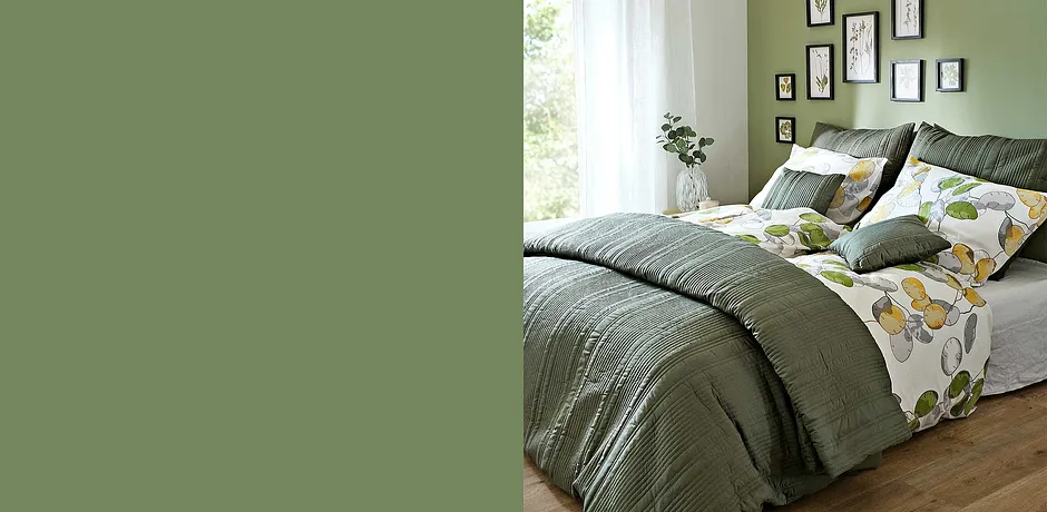 Chambre douillette avec parure de lit et coussins dans des tons verts. Le motif floral sur le linge de lit apporte de la fraîcheur.