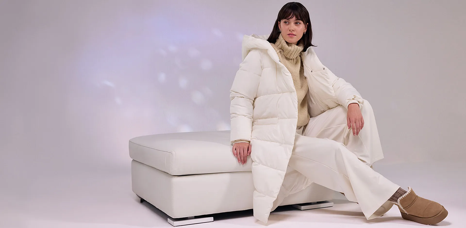 Manteau doudoune de couleur crème, pantalon blanc et bottines chaudes.