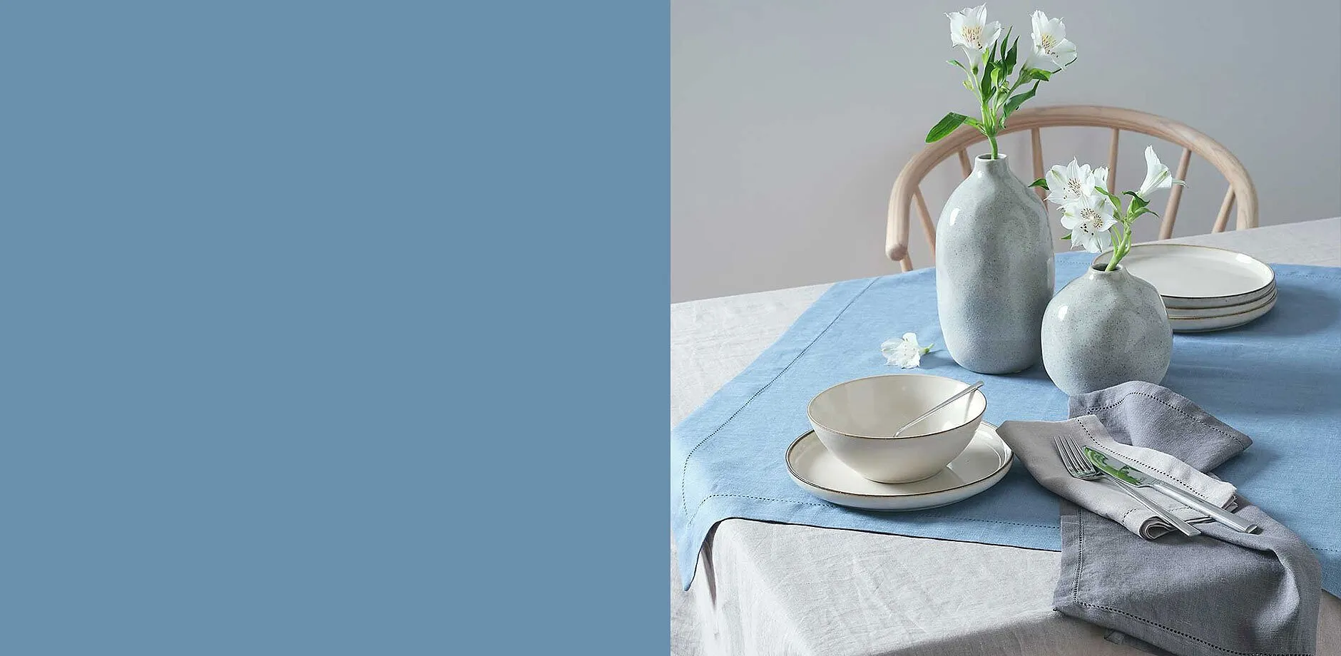 Une vaisselle élégante dans des tons pastel doux sur une nappe bleu clair.