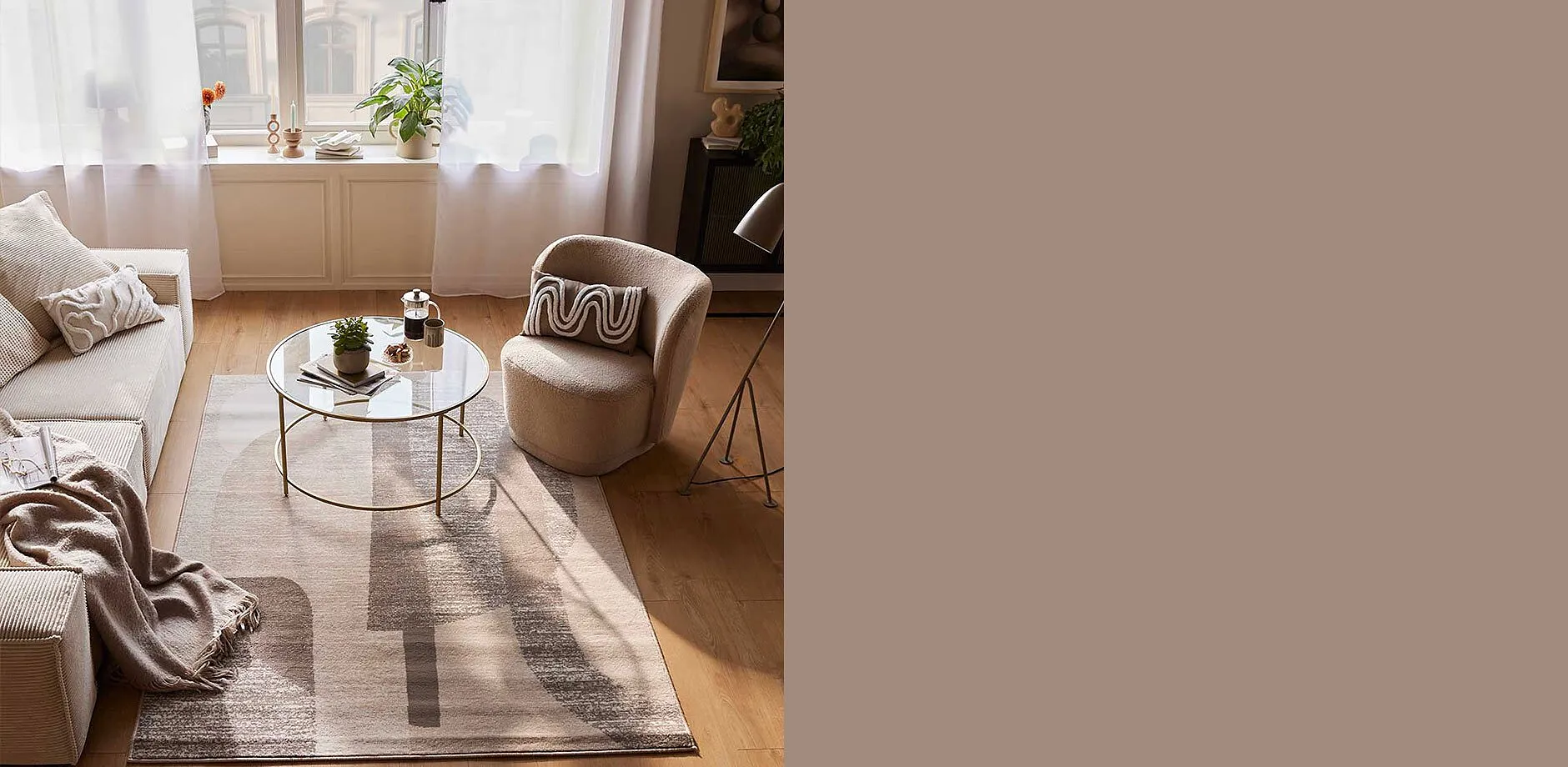 Un salon convivial avec un fauteuil beige, un plaid moelleux et un tapis stylé dans des tons chauds de terre.