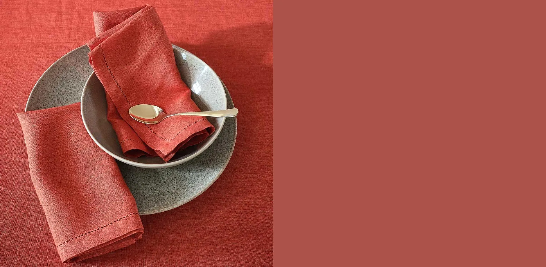 Décoration de table en rouge corail : serviette plié dans une assiette grise avec un couvert de couleur dorée.