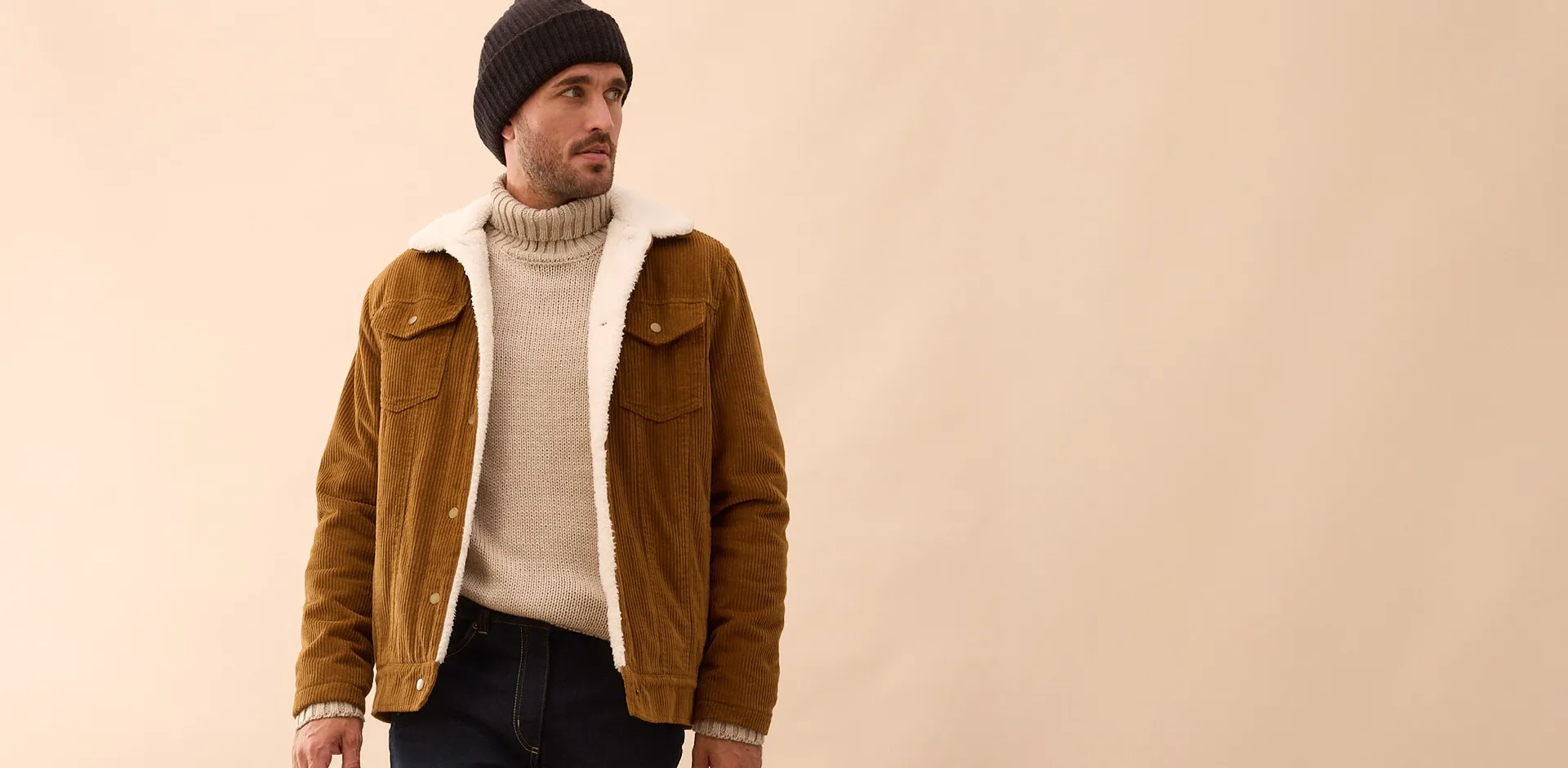 Un ensemble élégant composé d'une veste en daim marron, d'un pull à col roulé couleur crème et d'un bonnet noir.