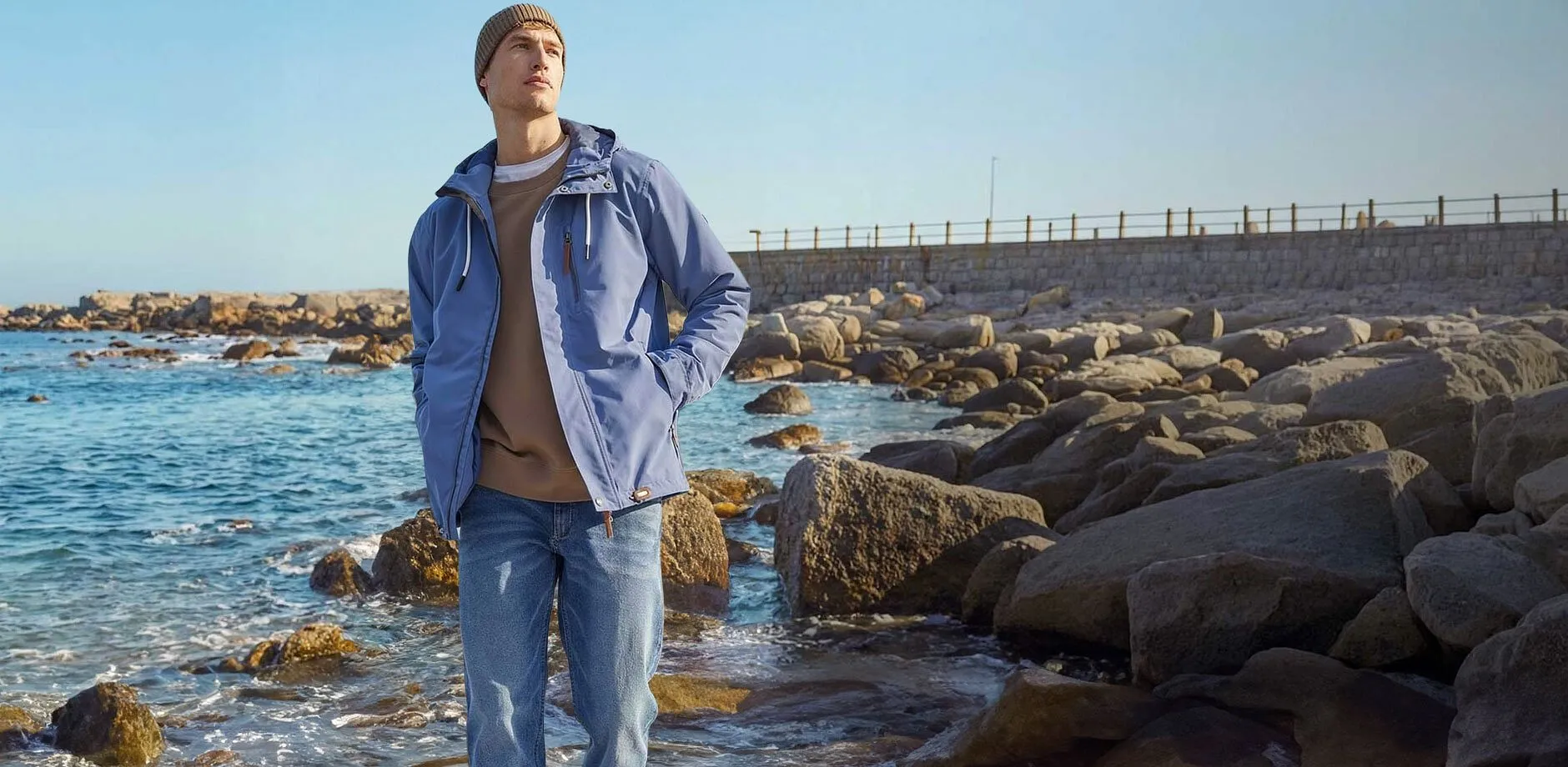 Veste fonctionnelle &eacute;l&eacute;gante bleue et jean de couleur claire &agrave; la plage.