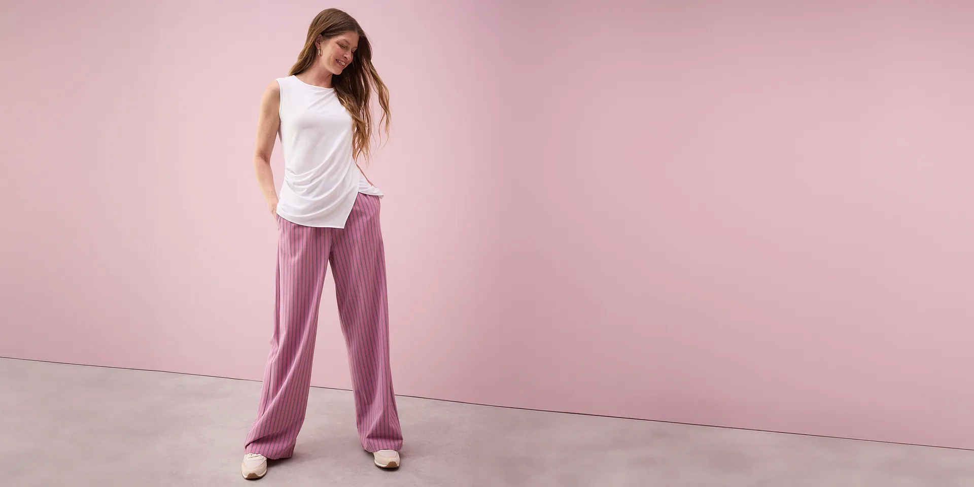Top blanc sans manches associ&eacute; &agrave; un pantalon palazzo rose ray&eacute;.