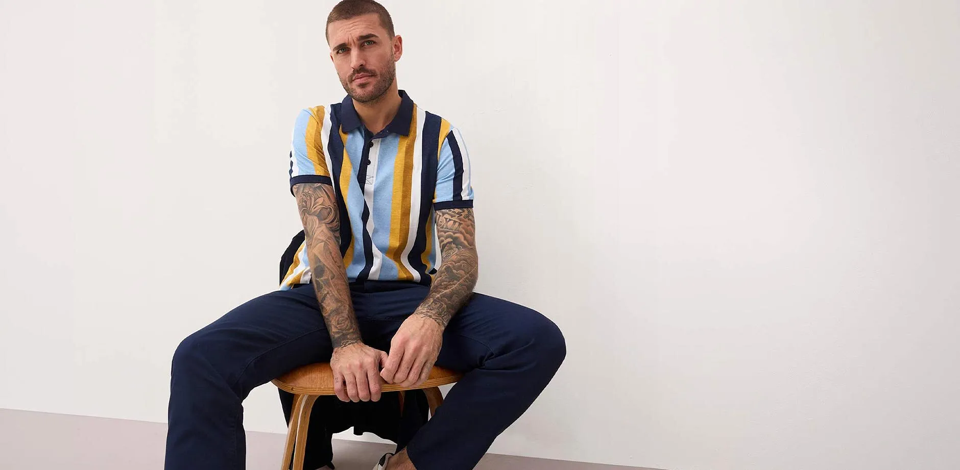 Polo ray&eacute; bleu, jaune et blanc. Pantalon bleu fonc&eacute;.