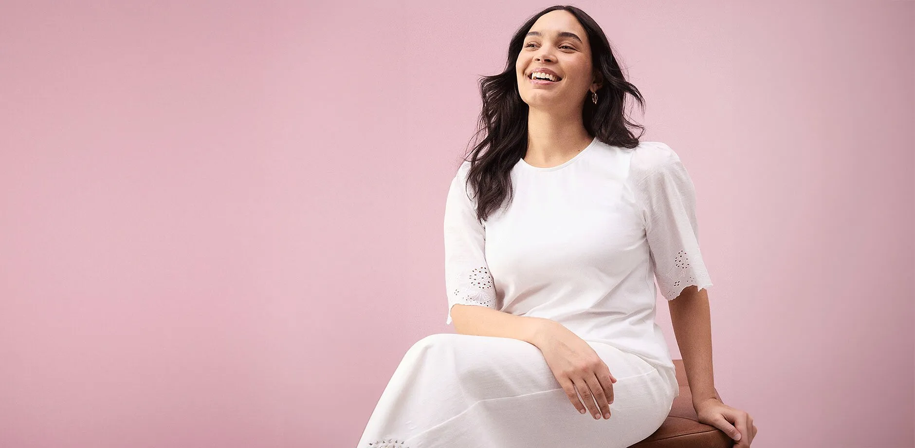 Une femme rayonnante dans une robe blanche &eacute;pur&eacute;e &agrave; manches courtes et broderie anglaise.