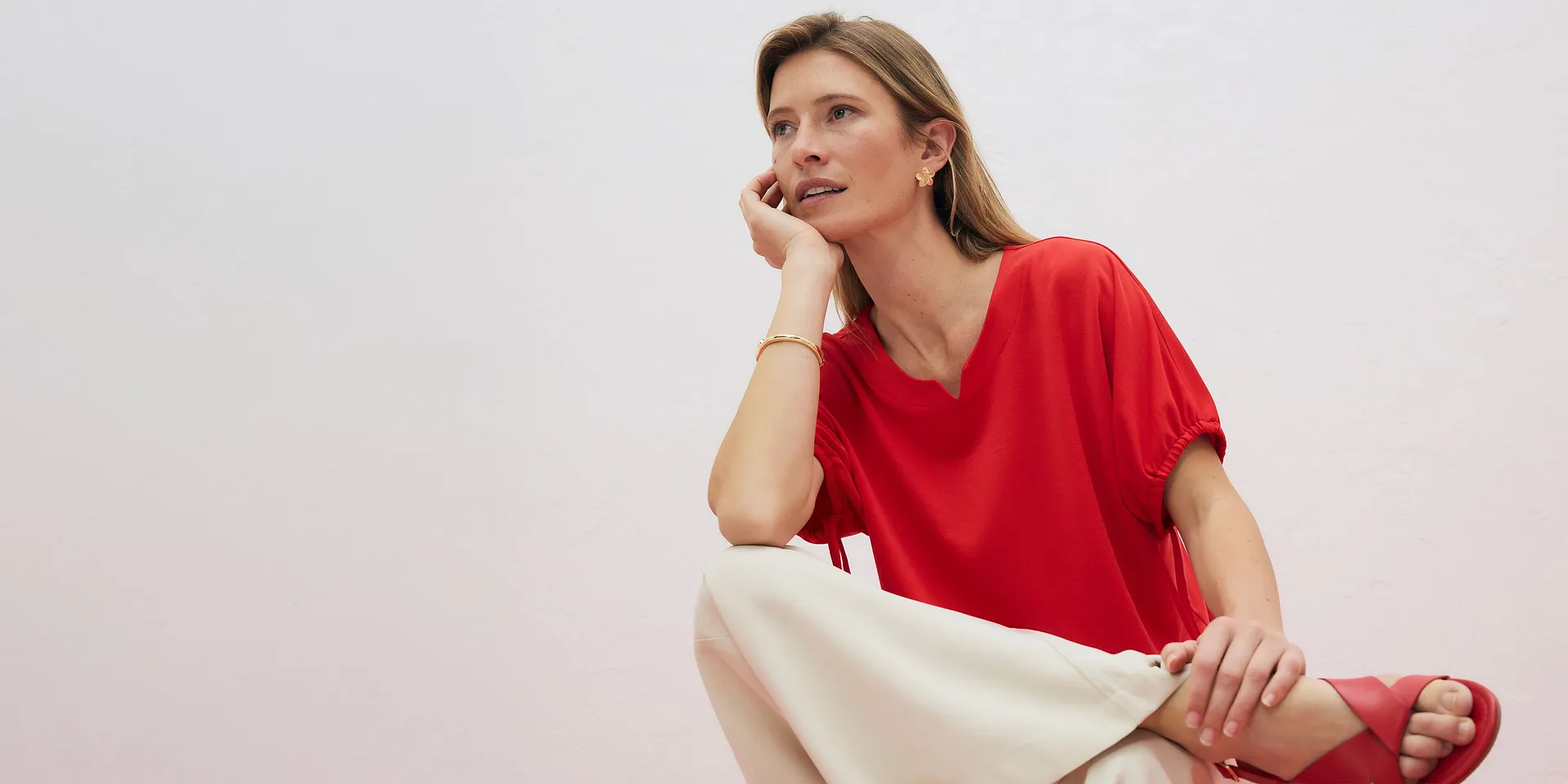 T-shirt rouge &eacute;l&eacute;gant avec d&eacute;collet&eacute; en V, associ&eacute; &agrave; un pantalon de couleur claire.