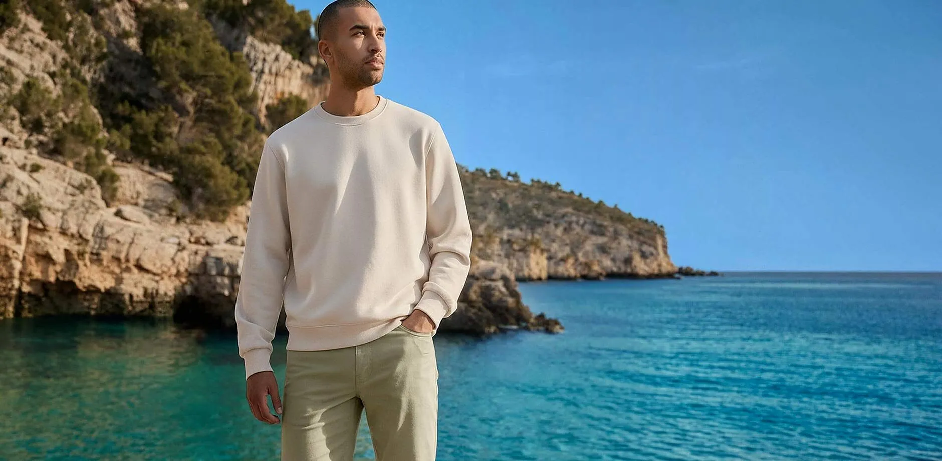 Sweat de couleur cr&egrave;me et pantalon clair en bord de mer.