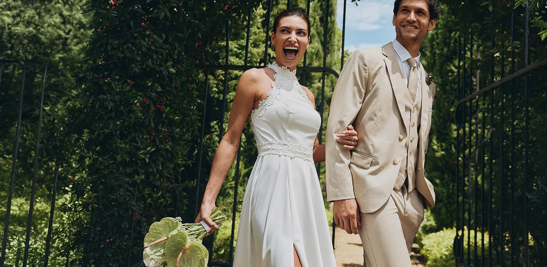 Jeunes mari&eacute;s &eacute;l&eacute;gants par une belle journ&eacute;e ensoleill&eacute;e : la mari&eacute;e en robe blanche, le mari&eacute; en costume beige.
