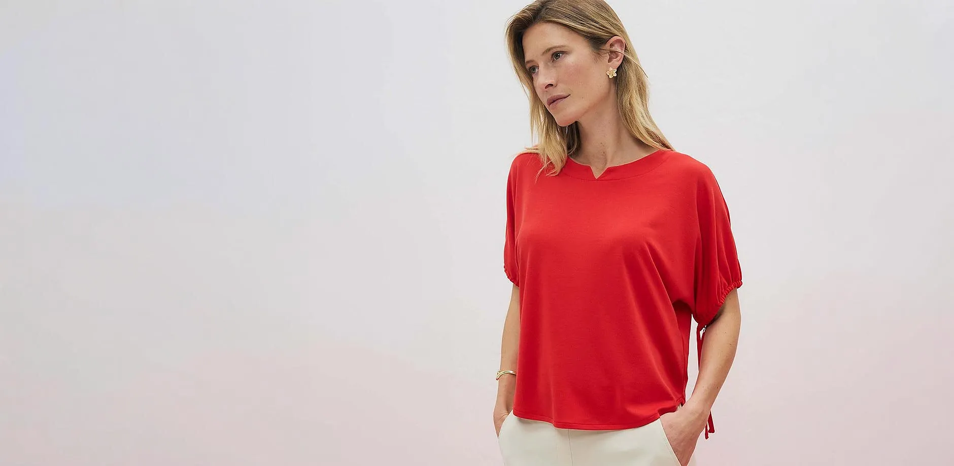 T-shirt rouge &eacute;l&eacute;gant avec d&eacute;coupe en V au d&eacute;collet&eacute;, associ&eacute; &agrave; un pantalon de couleur claire.