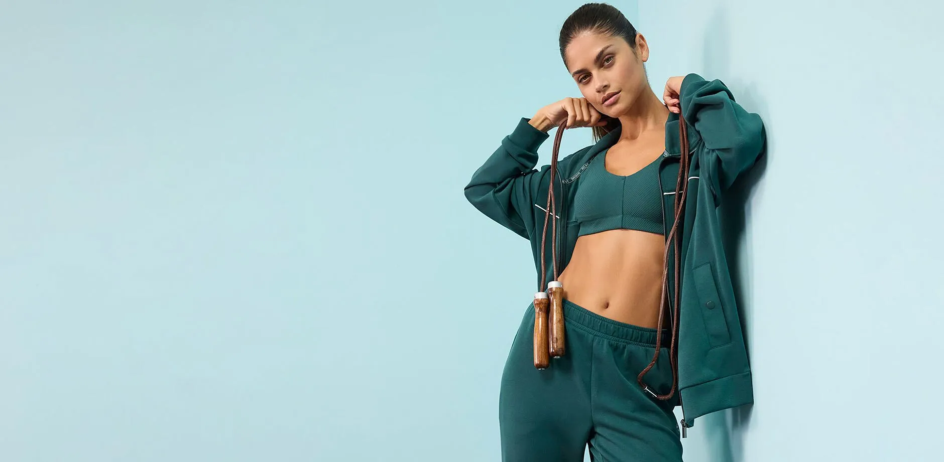 Surv&ecirc;tement vert avec veste &agrave; capuche, brassi&egrave;re et pantalon assorti.