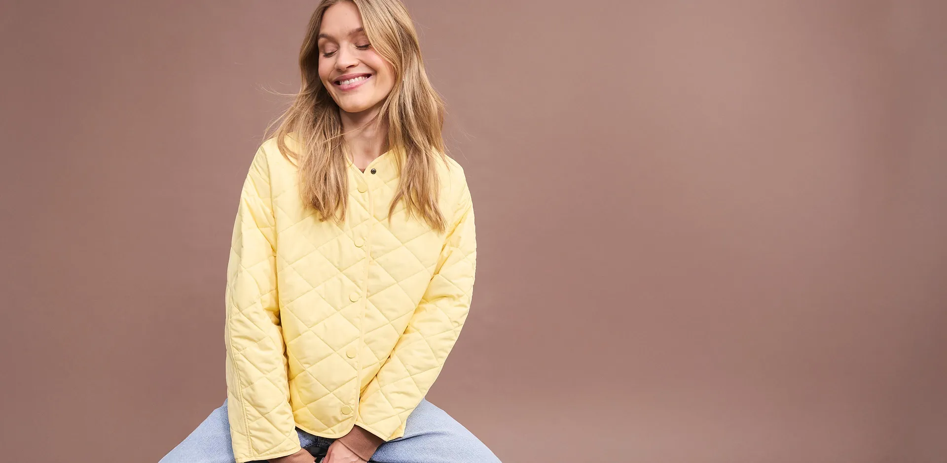 Veste matelass&eacute;e oversize jaune associ&eacute;e &agrave; un pantalon bleu.