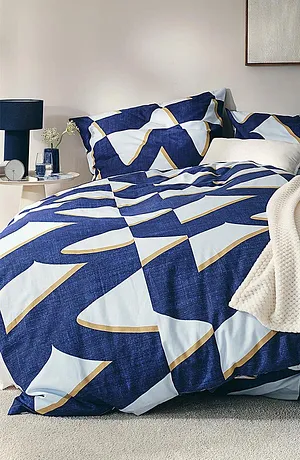 Parure de lit géométrique en bleu et blanc, rehaussée d'une couverture de couleur crème.