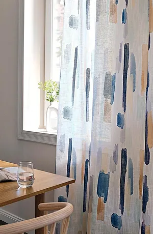 Un voilage léger avec un motif coups de pinceau dans des tons bleu gris décore la fenêtre et laisse entrer un peu de lumière.