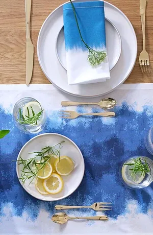 Un chemin de table bleu avec dégradé de couleur décore la table, complété d'une vaisselle blanche et de couverts raffinés.