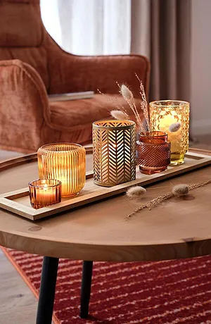 Ambiance d'automne chaleureuse avec des bougies et des décorations dorées sur une table en bois rustique.
