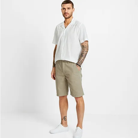 Chemise manches courtes à motif, short beige et tennis blanches.