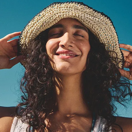 Un chapeau de paille tressé et un haut blanc léger pour une ambiance de vacances estivale.