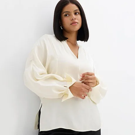 Blouse blanche élégante à col en V et manches amples.
