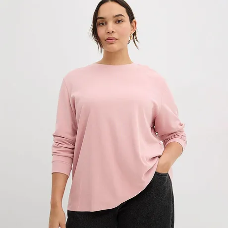 Un T-shirt à manches longues rose dragée à col rond complète à merveille le pantalon foncé.