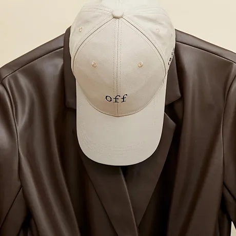 Une casquette beige et une veste enduite marron suspendues à un cintre. 