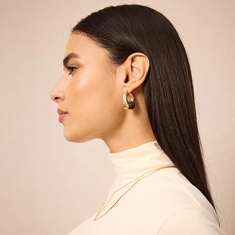 Pull à col roulé couleur crème, sobre et chic. Une paire de boucles d'oreilles de couleur dorée exclusives.