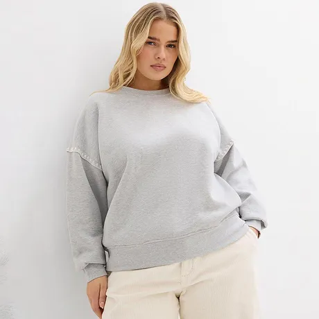 Sweat-shirt gris associé à un pantalon clair.