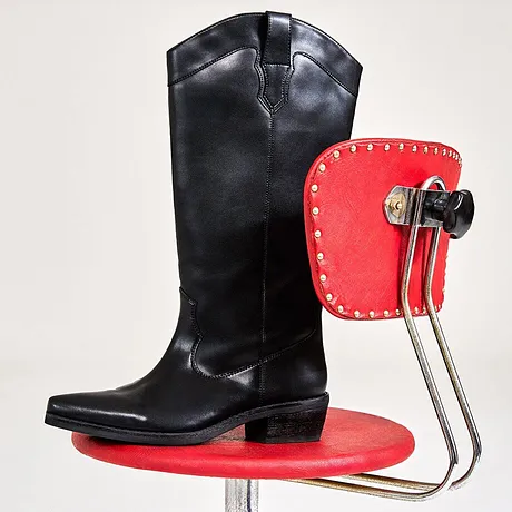 Bottes noires à tige haute sur une chaise rouge.