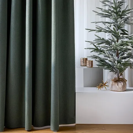 Des rideaux foncés encadrent le sapin de Noël.