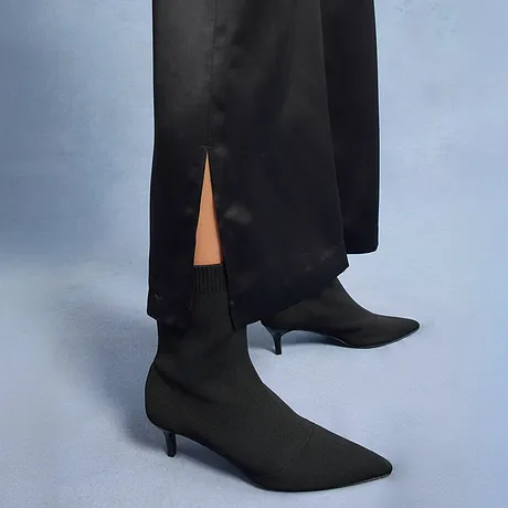 Pantalon noir élégant avec fente, associé à des bottines pointues.