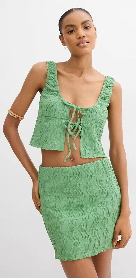 Ensemble texturé vert, composé d’un top et d’une jupe près du corps.