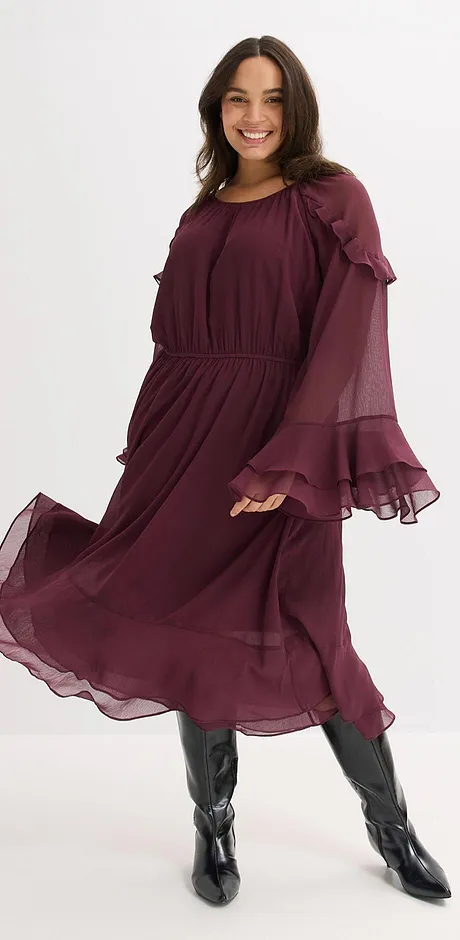 Robe rouge bordeaux en tissu fluide avec manches amples et bottes noires.