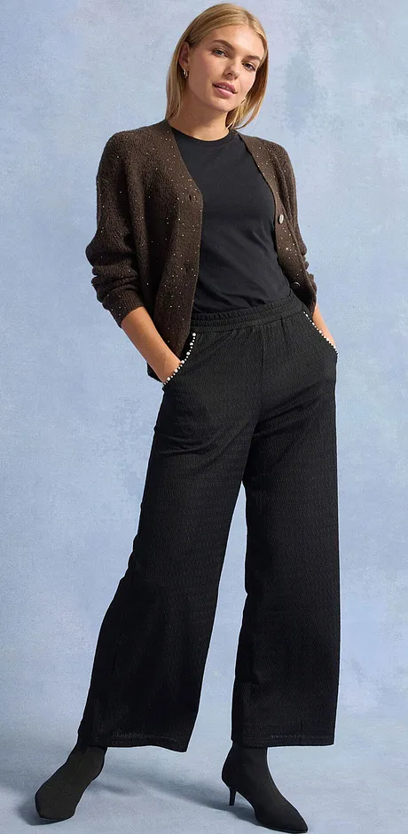 Pantalon noir, T-shirt et gilet en maille brillant.