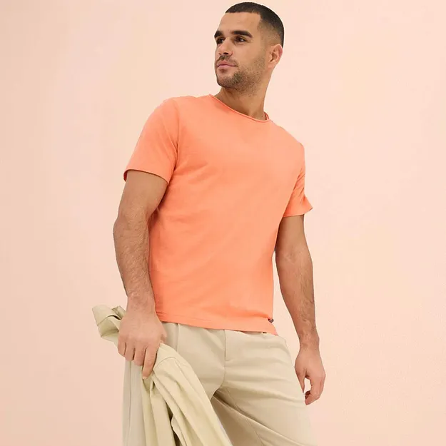 T-shirt couleur p&ecirc;che associ&eacute; &agrave; un pantalon de couleur claire et un pull assorti. 