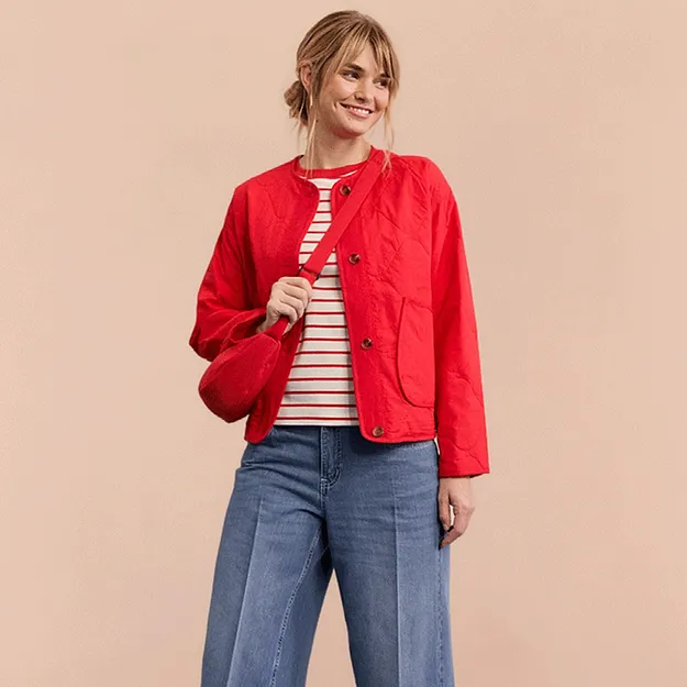 Veste rouge par dessus un T-shirt ray&eacute;, jean large et sneakers rouge.