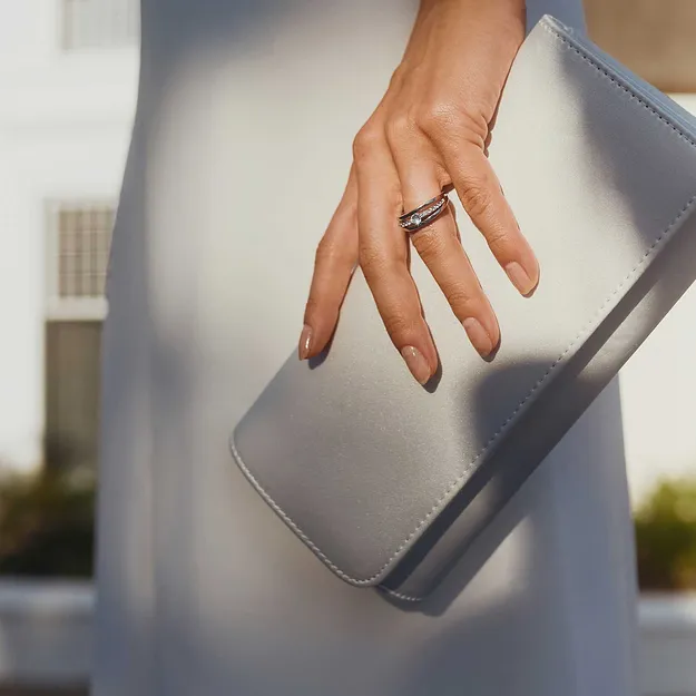 Robe blanche associ&eacute;e &agrave; une pochette claire et une bague raffin&eacute;e.
