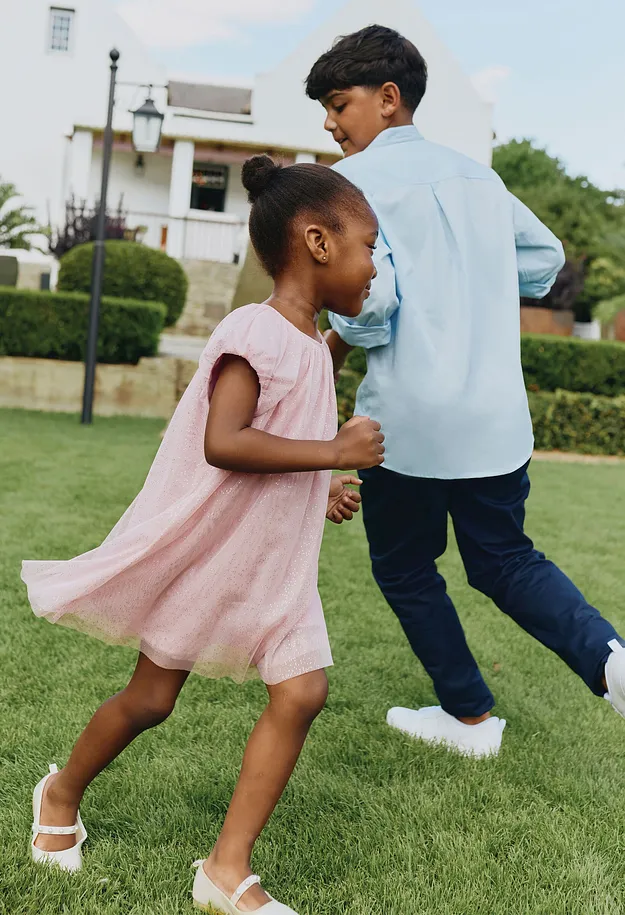 Une jeune fille en robe rose s'amuse dans le jardin.