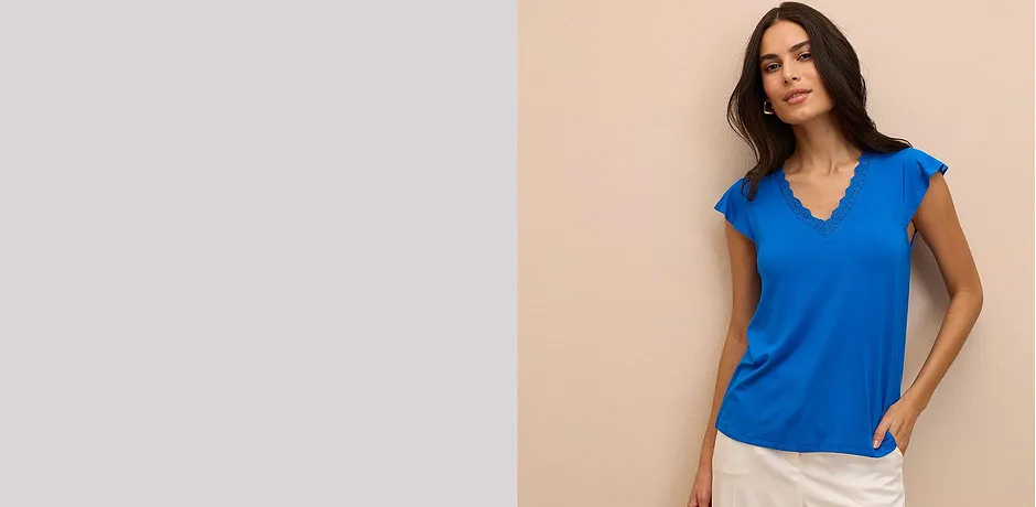 Top bleu éclatant avec décolleté en V et manches courtes, associé à un pantalon clair.