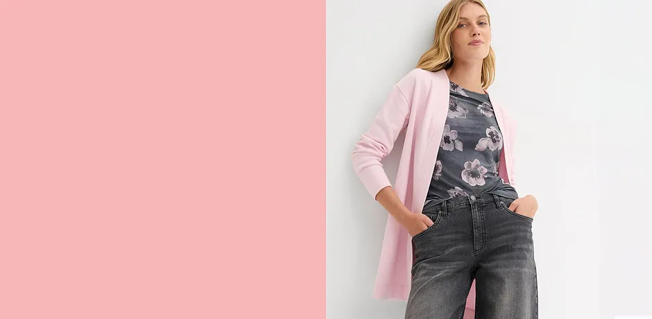 Gilet long rose sur un jean sombre. Un contraste élégant entre des teintes claires et foncées.