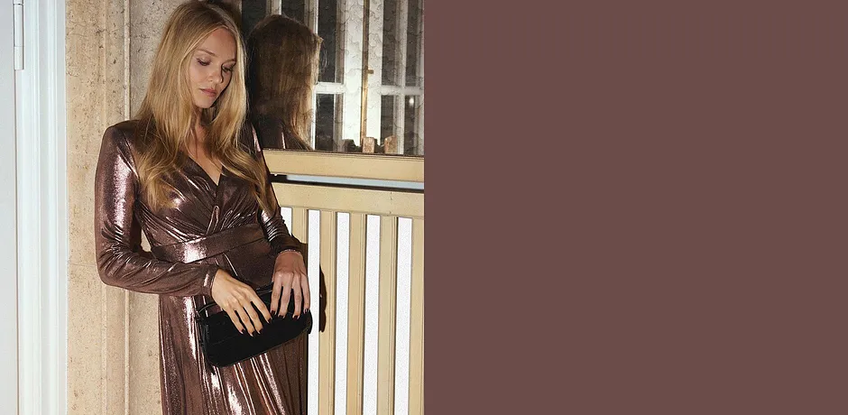 Robe scintillante avec décolleté en V associée à un sac noir.