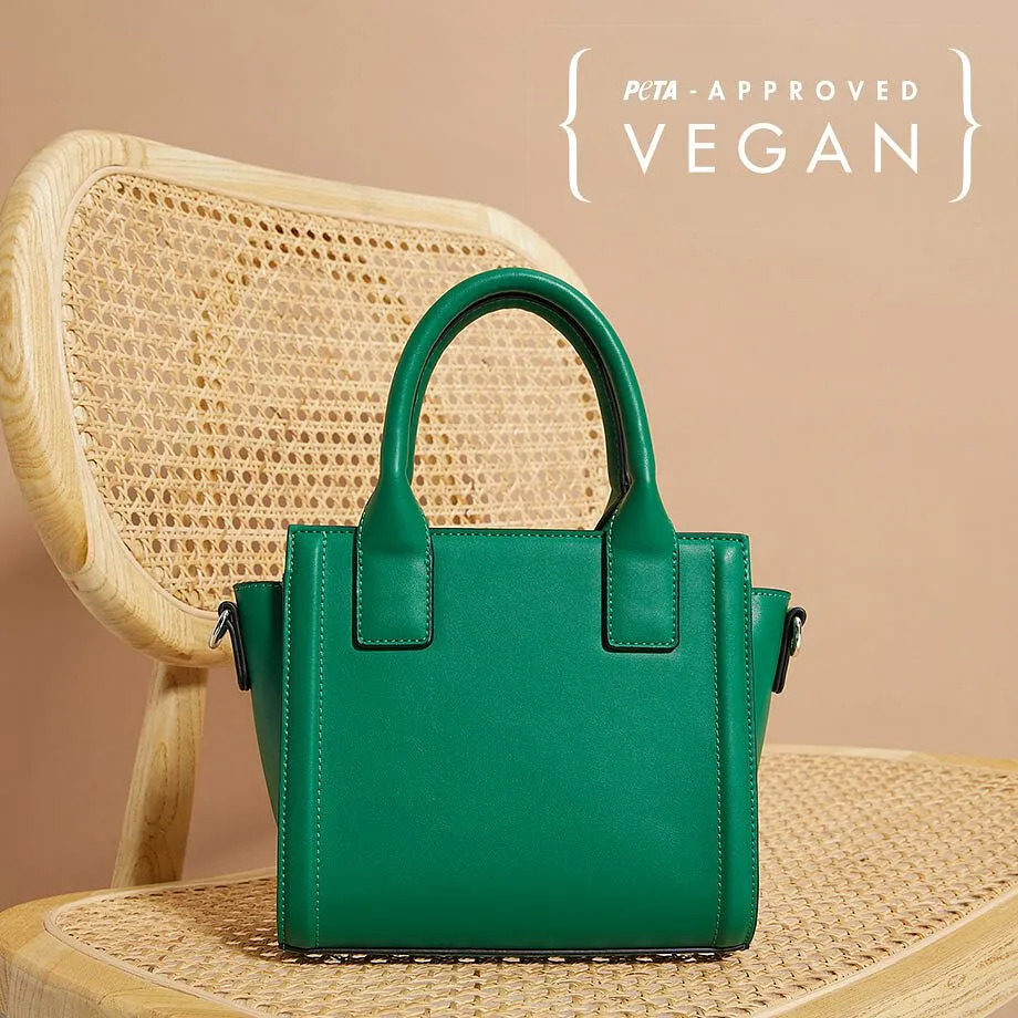 Un petit sac à main vert en cuir vegan posé sur une chaise tressée.