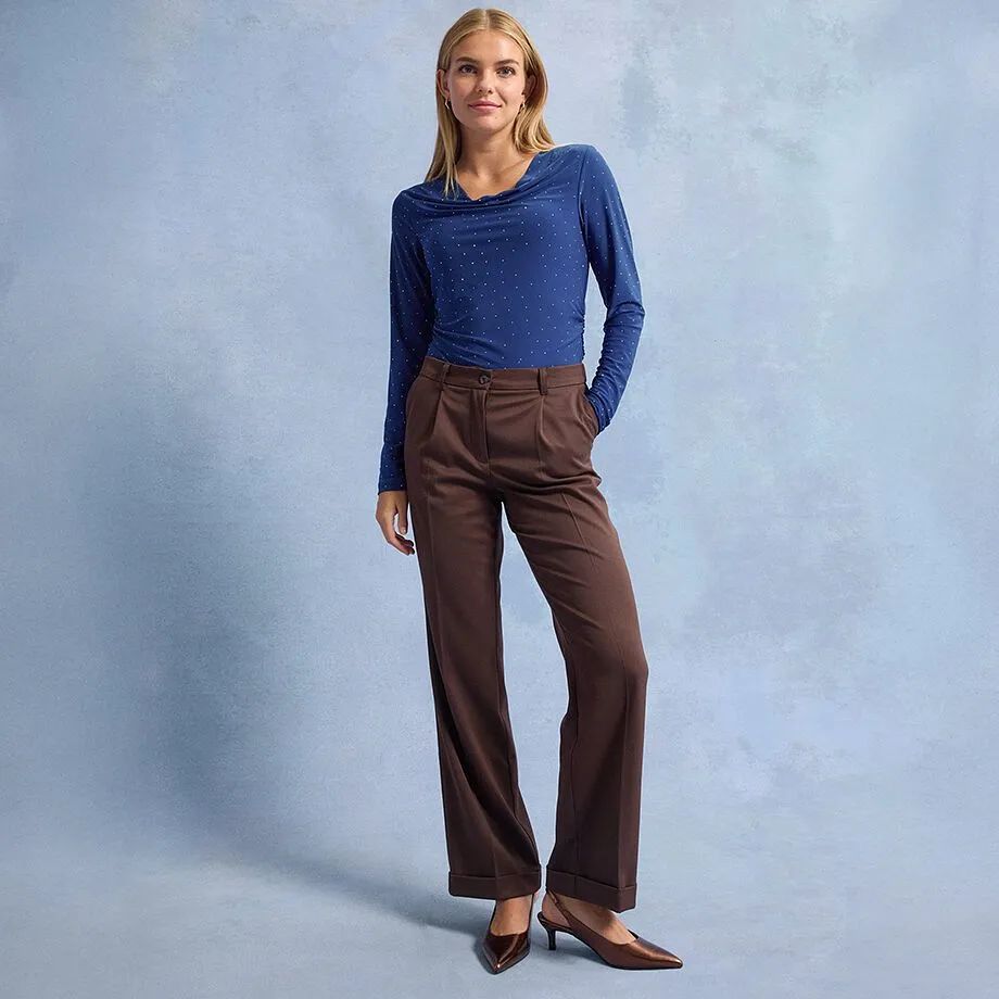 T-shirt à manches longues bleu à pois, pantalon coupe large marron et chaussures marron à bout pointu. 