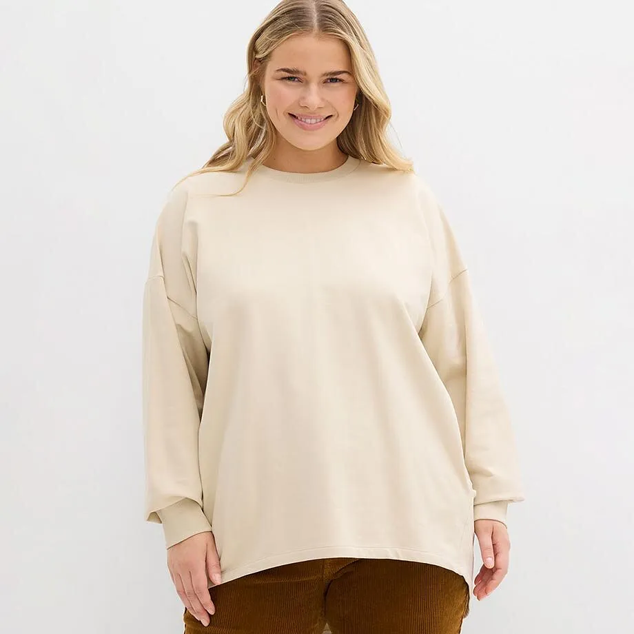 Sweat de couleur crème à encolure ronde, associé à un pantalon marron.