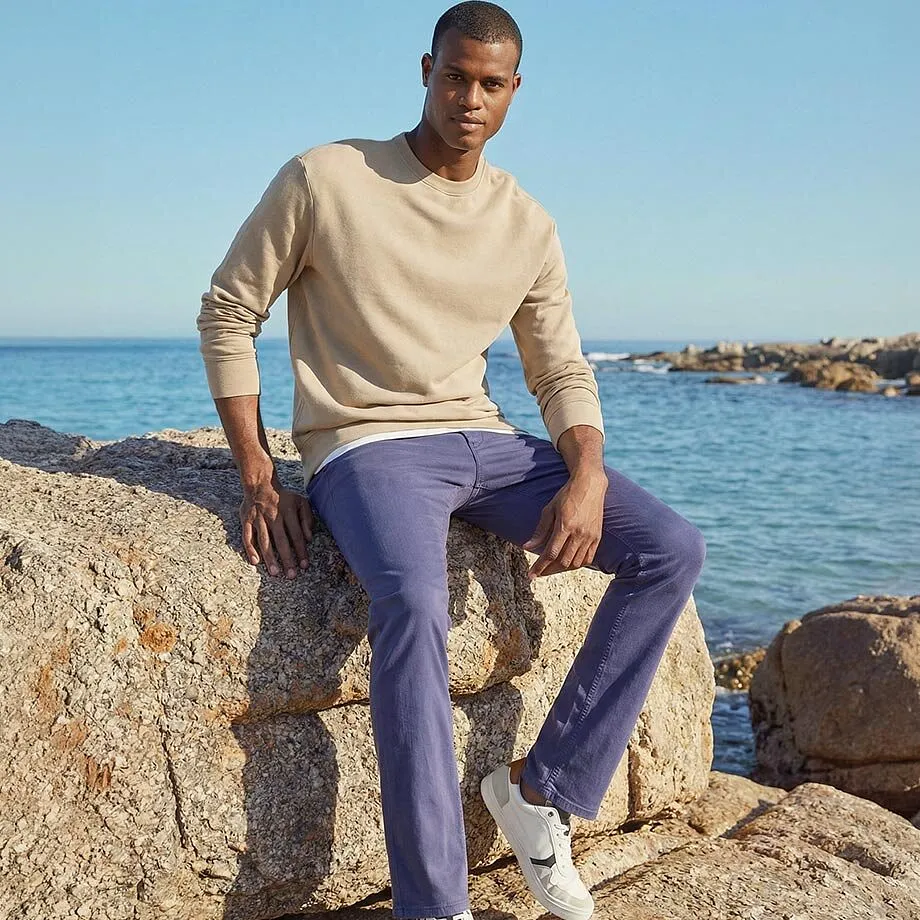 Pull beige et pantalon violet en parfaite harmonie avec le d&eacute;cor marin.