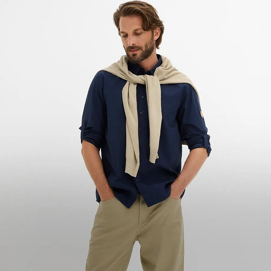 Chemise bleu fonc&eacute; avec manches retrouss&eacute;es et pantalon beige.