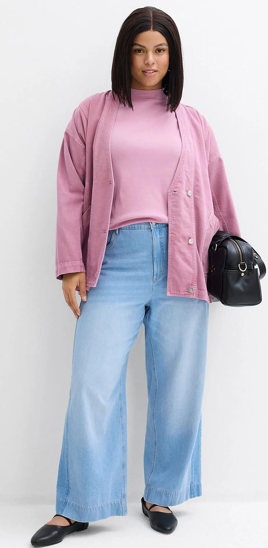 Gilet en maille rose sur un top rose pastel, compl&eacute;t&eacute; d'un jean bleu clair et de chaussures noires.